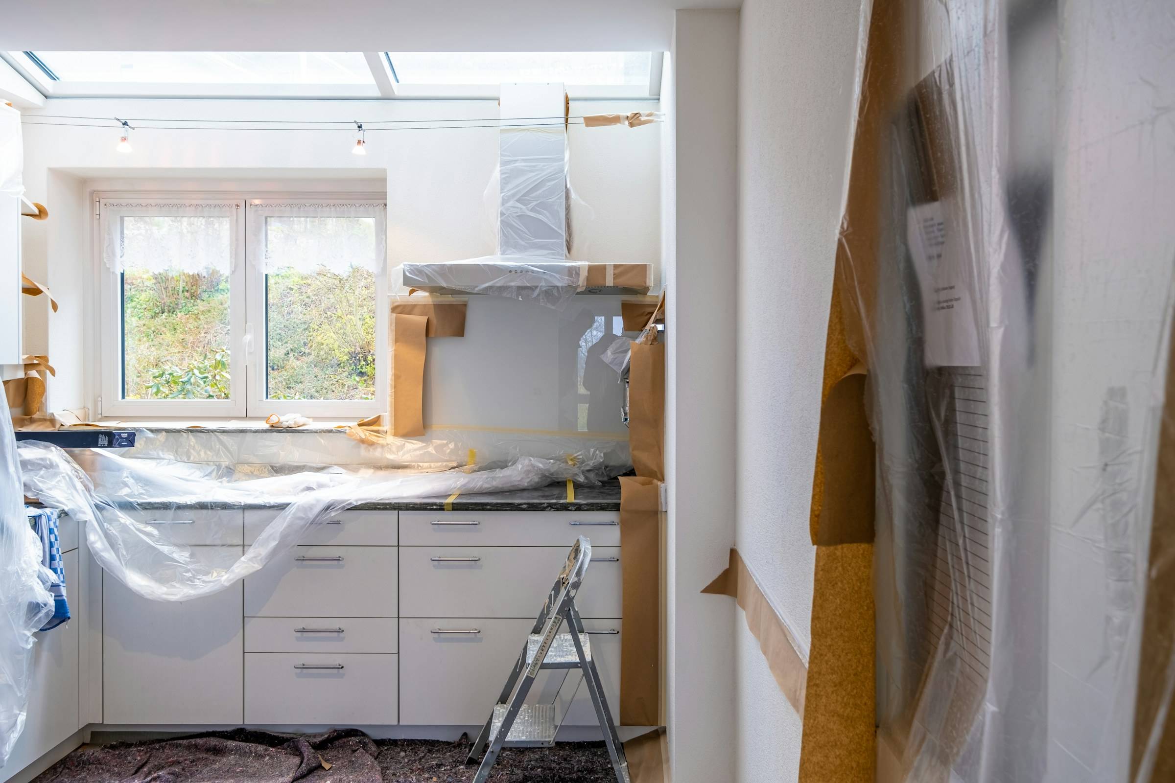 Kök under renovering med skyddsplast över skåpen